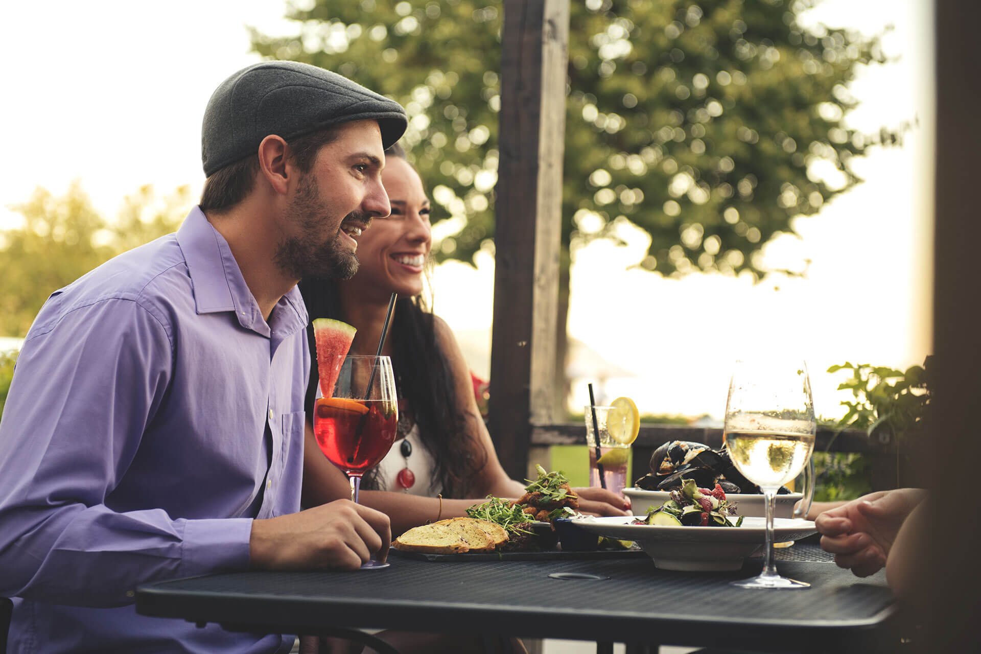 Jeune couple sur une terrasse au centre-ville dégustant un verre et un bon repas.