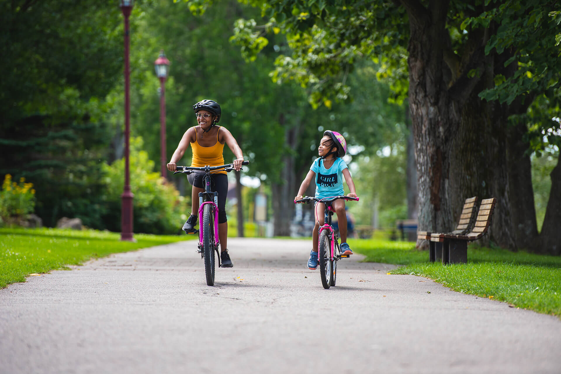 Une fillette et une jeune femme faisant du vélo au Parc de la Rivière-aux-Sables.