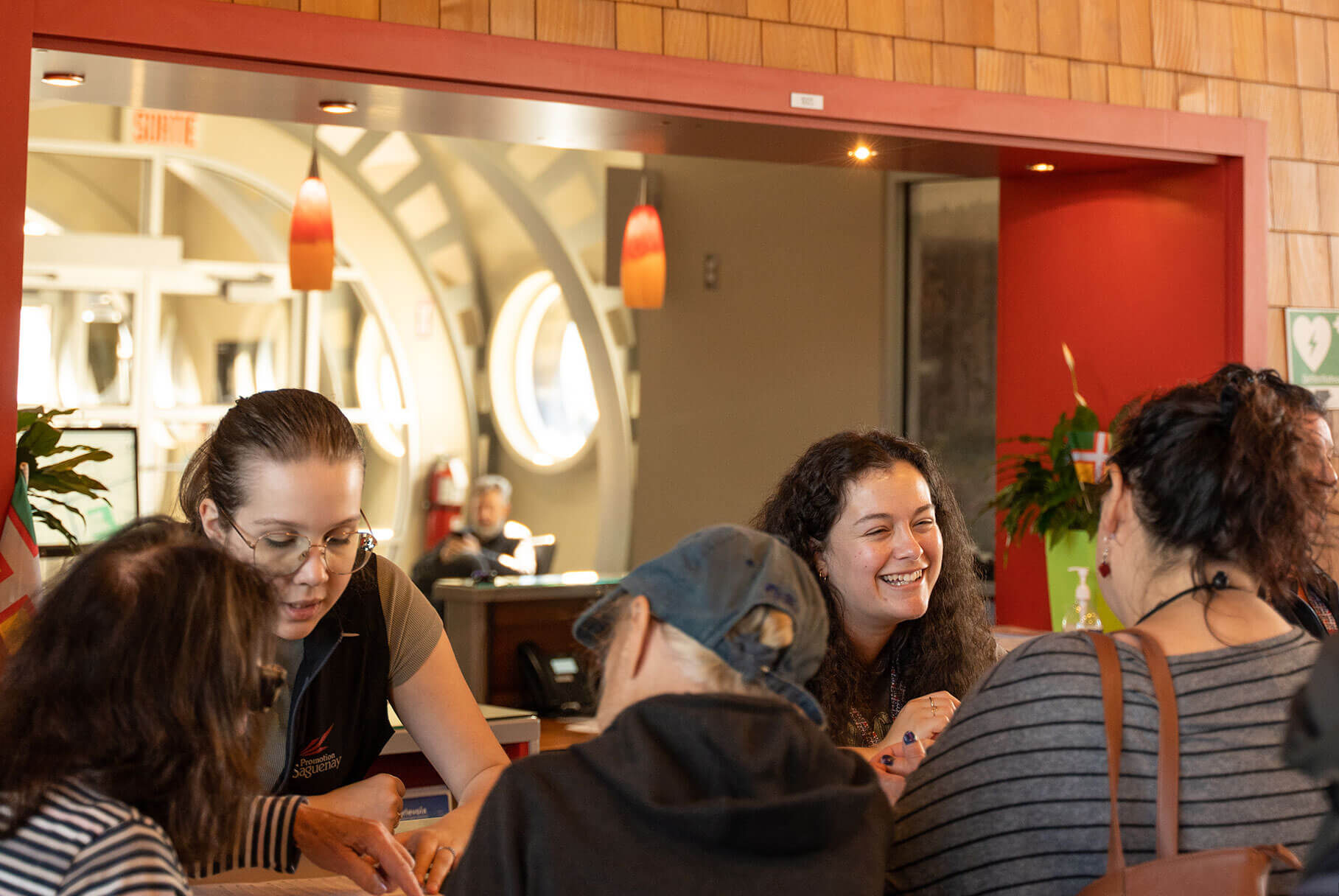 Deux conseillères discutant avec des touristes dans un bureau d'information touristique de Saguenay.